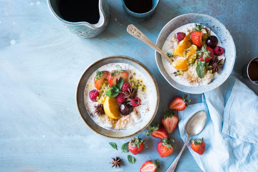 Deux bols de céréales pour le petit-déjeuner et des fruits frais avec une cafetière.